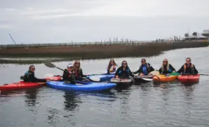 Group of women in kayaks and life jackets on the marsh in Murrells Inlet on an overcast day