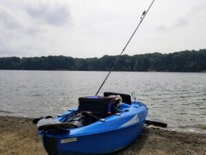 Blue fishing kayak with rods pulled up on the shore