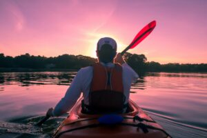 Kayaker in a life jacket paddling at sunset